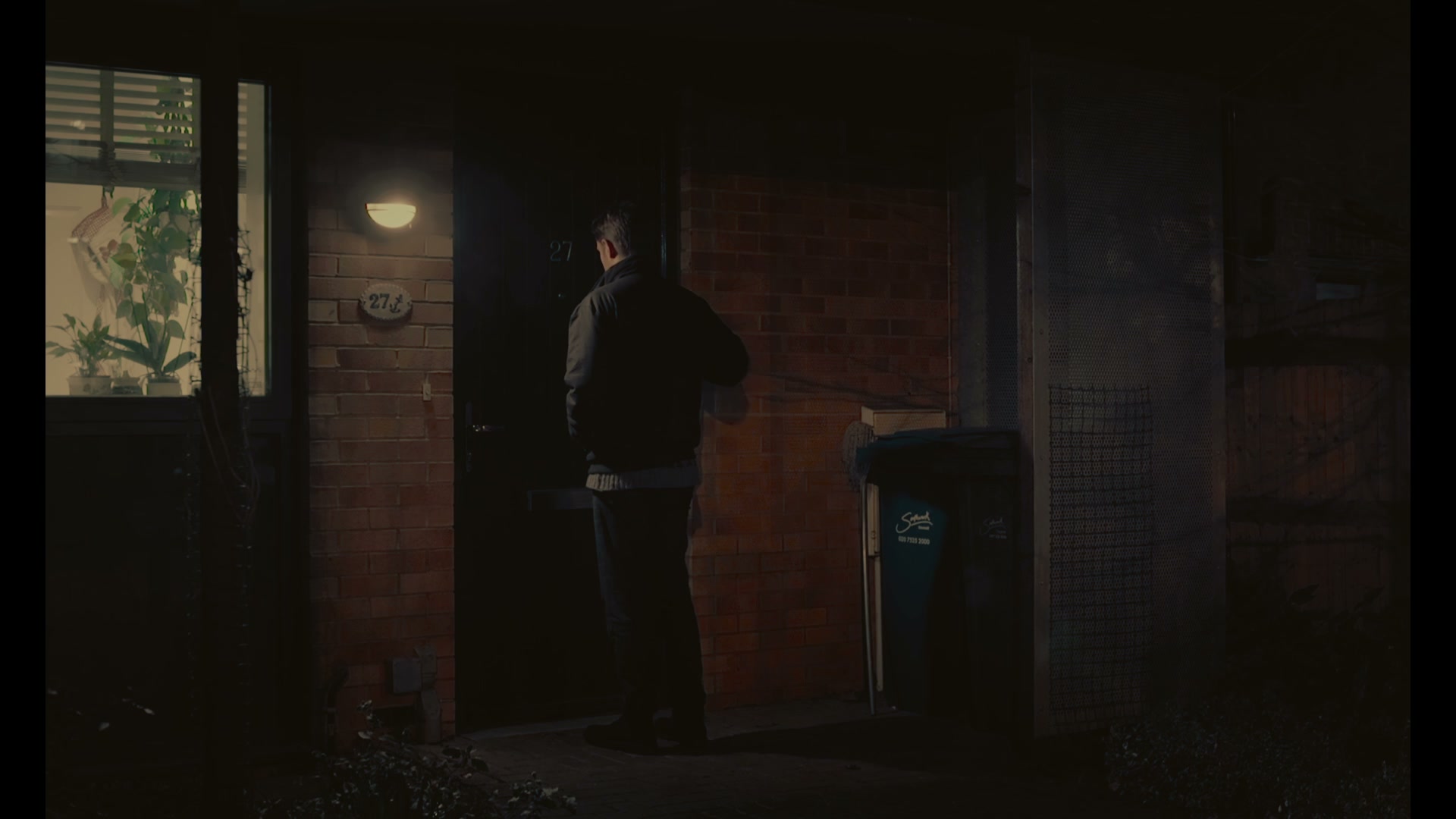 Walk by Water · film still: a figure at a doorway at night